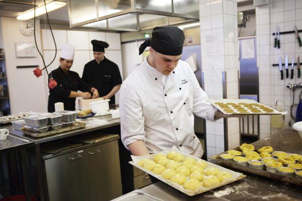 Kuvituskuva, kokki asettelee peltejä pöydälle