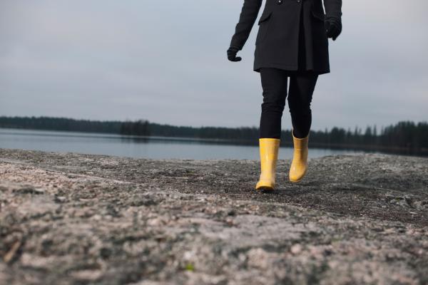 Henkilö kävelee kalliolla keltaisissa kumisaappaissa
