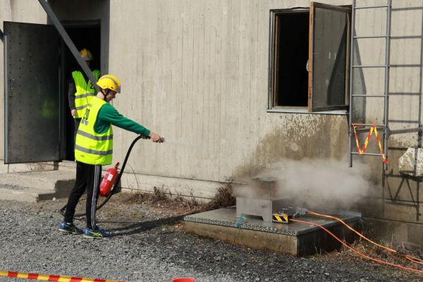 Oppilas sammuttaa vaahtosammuttimella laatikkoa.