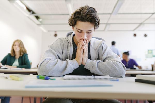 A young student ponders at the table.