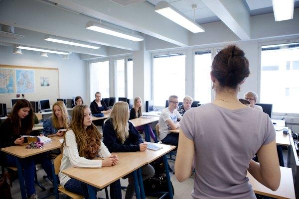 Kuvituskuva, jossa opettaja seisoo luokan etuosassa ja opettaa oppilaita. 