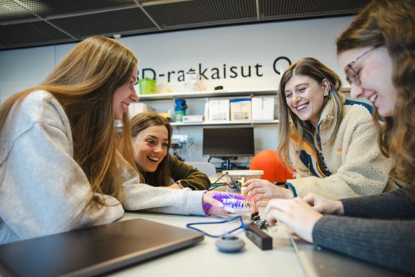 A group of four students collaborates around a table.