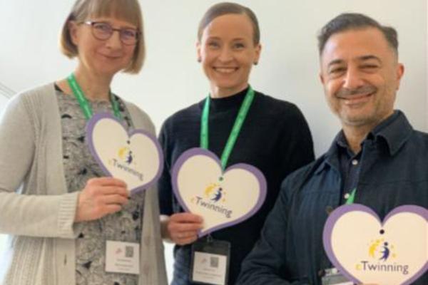 eTwinning-innovaattorit 2026, kolme aikuista ihmistä vierekkäin pahviset sydämet kädessä