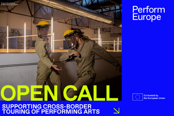 Teksti Open call - supportinh cross-border touring of performing arts. Taustalla kuva kahdesta hitsaajan kypärään pukeutuneesta esiintyjästä.