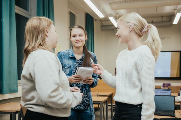 Kolme oppilasta luokassa.