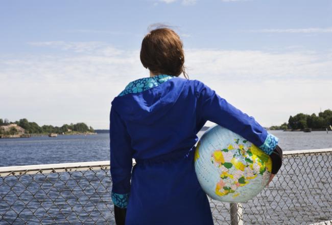 Kuvituskuva, tyttö jolla maapallo kainalossa