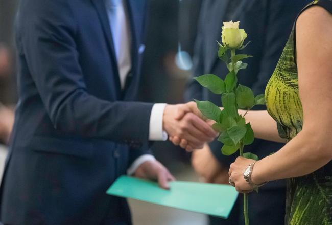 Kuvituskuva, ruusu ojennetaan valmistuneelle