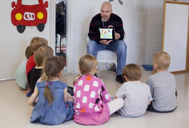 Kuvituskuva, opettaja näyttää lapsille tabletilta sisältöä