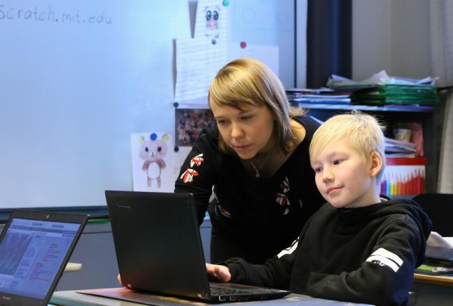 Kuvituskuva, opettaja ja oppilas tietokoneen ääressä