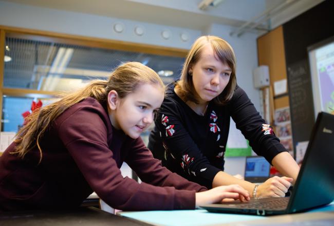 Kuvituskuva, tyttö ja opettaja tietokoneella