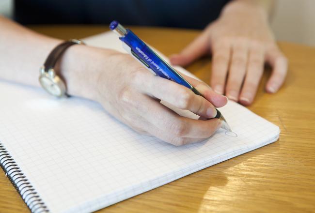 Kuvituskuva, nainen kirjoittaa muistiinpanoja muistivihkoon