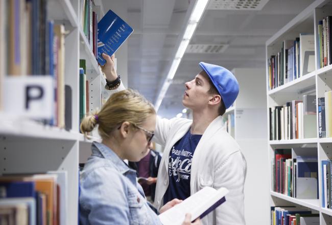 Kuvituskuva, nuoret tutkimassa kirjoja kirjastossa