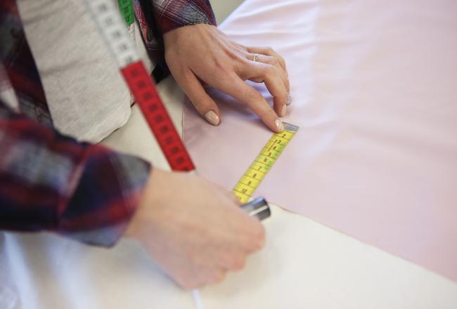 Kuvituskuva, opiskelija mittaa kangasta