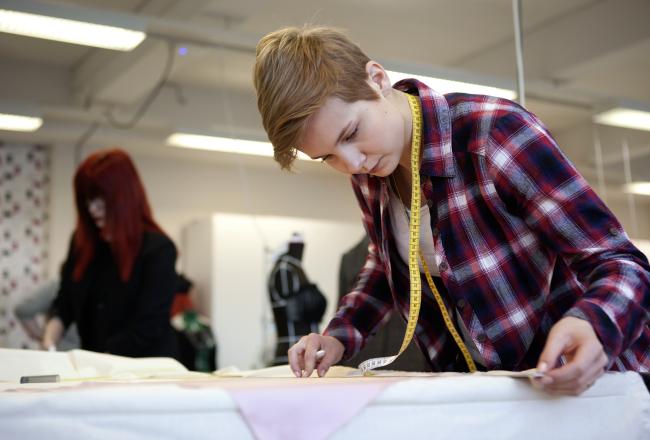 Kuvituskuva, opiskelija mittaa kangasta