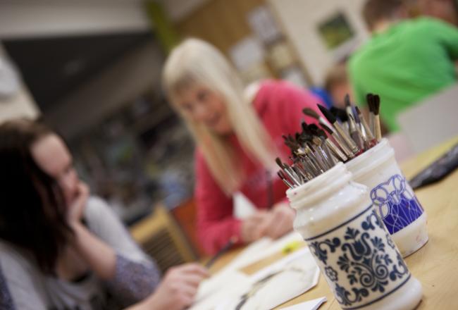 Paint brushes in jars in a visual arts classroom.