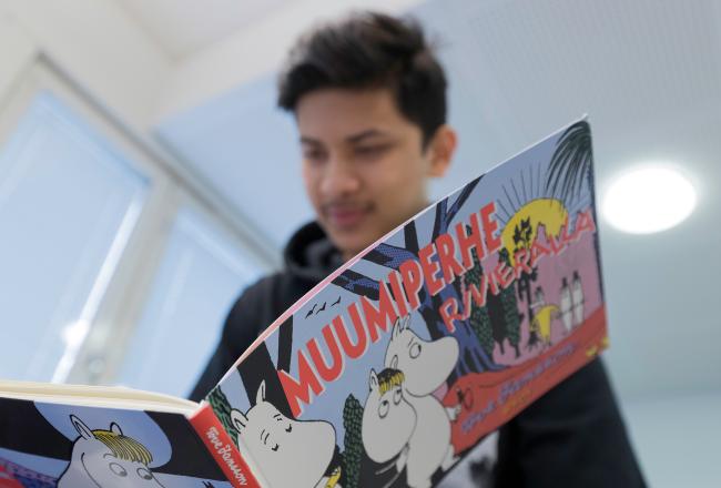 Kuvituskuva, poika lukee muumi-kirjaa