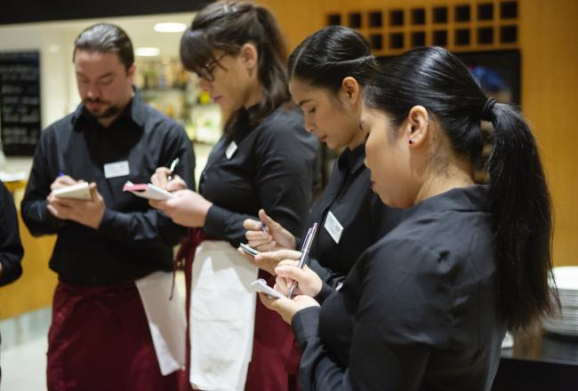 Ravintola-alan opiskelijat tekevät muistiinpanoja opetusravintolassa