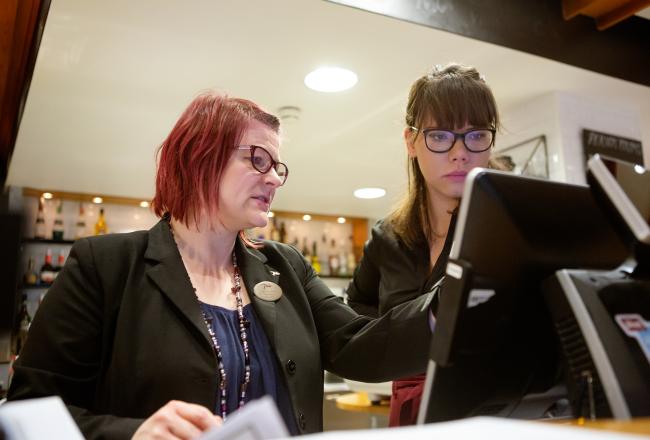 Opettaja ja opiskelija opetusravintolan kassakoneen ääressä