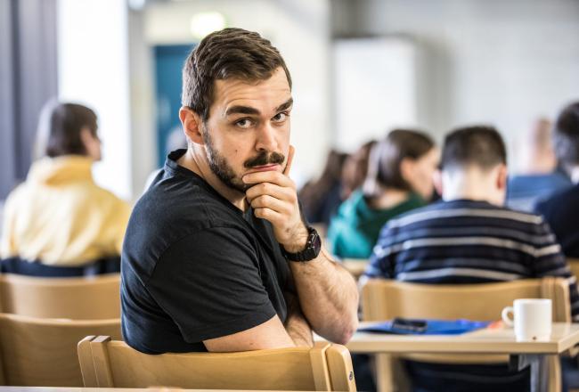 Kuvitus kuvassa miesopiskelijalla miettivä ilme