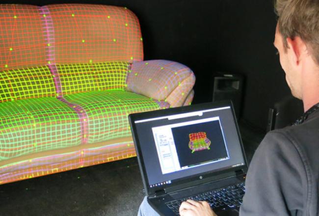 Opiskelija tekee digitaalista kuviointia sohvaan tietokoneella.