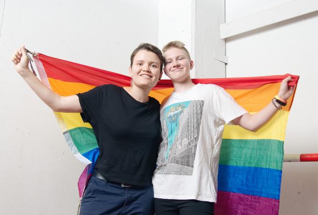 Två unga människor som håller en regnbågsflagga