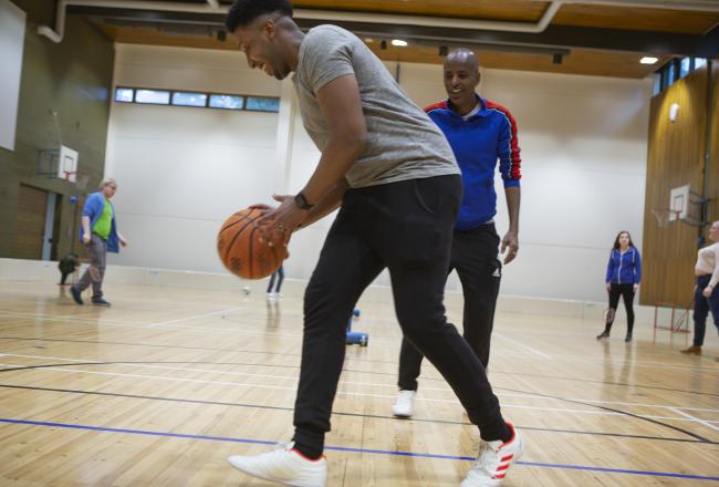 Två manliga elever spelar basket på ett skolgym