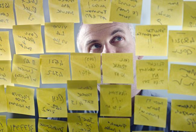 Mannen tittar på post -it -klistermärkena som fästs på glasväggen