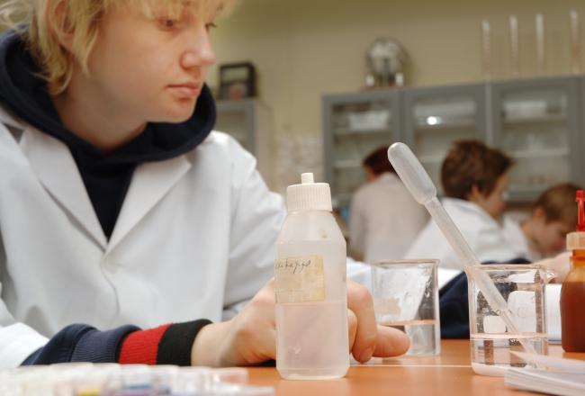 Oppilas kemian tunnilla koeputkien ja pipettien parissa työskentelemässä