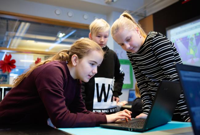 Oppilaat työskentelevät kannettavan tietokoneen äärellä.