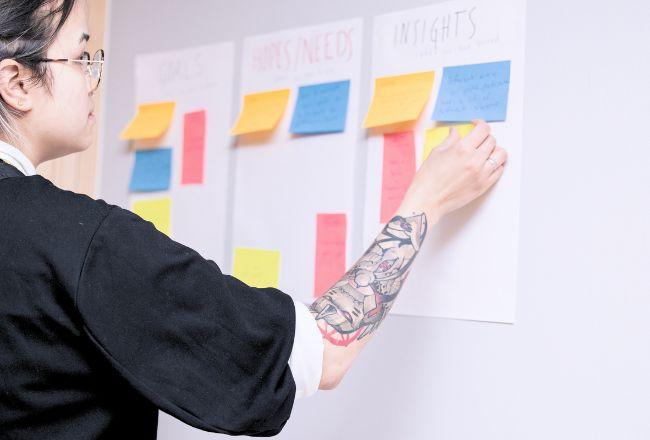 Henkilö liimaa post it -lappuja seinälle.