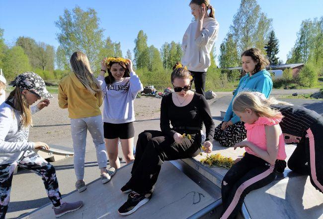 Joukko nuoria tekee seppeleitä ja kiipeilee.