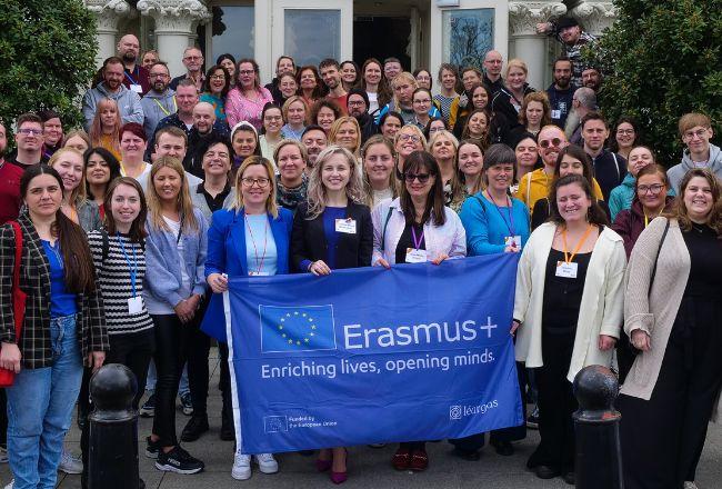 Suuri ihmisjoukko Erasmus+ -lipun taakse kokoontuneena.