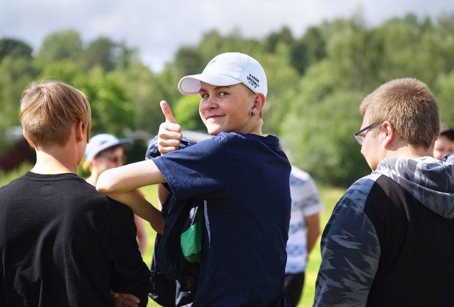 Nuori on kääntynyt kameraa kohti ja näyttää peukaloa.