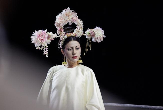 Turandot -oopperan päähenkilö, naislaulaja  valkoisessa kiinalaisessa juhla-asussa ja vaaleanpunaisista kukista kootussa päähineessä