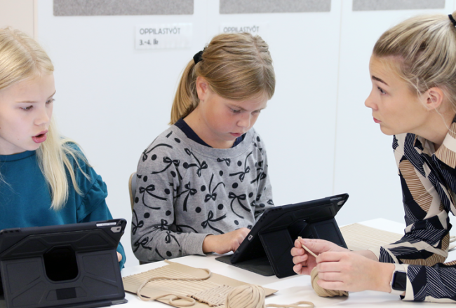 Opettaja ohjaa oppilaita, jotka työskentelevät tableteilla