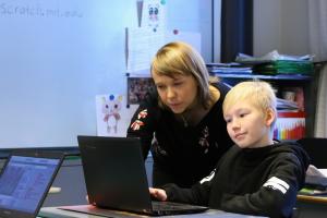 Kuvituskuva, opettaja ja oppilas tietokoneen ääressä