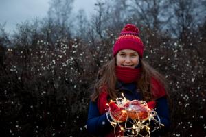 Myssypäinen tyttö käsissään punaiset lapaset ja kaamosvalot