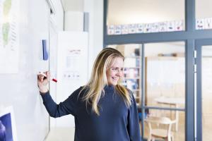 Nuori opettaja oppitunnilla tussitaulun edessä