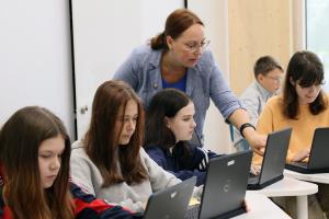 Opiskelijoita tietokoneella opettajan kanssa