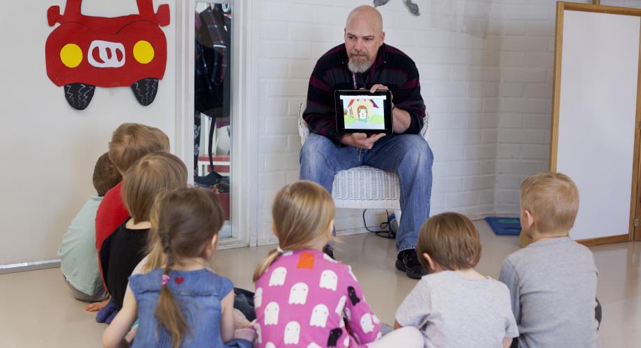 Kuvituskuva, opettaja näyttää lapsille tabletilta sisältöä