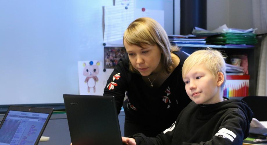 Kuvituskuva, opettaja ja oppilas tietokoneen ääressä