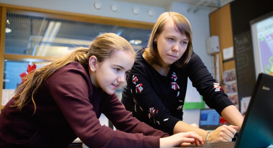 Kuvituskuva, tyttö ja opettaja tietokoneella