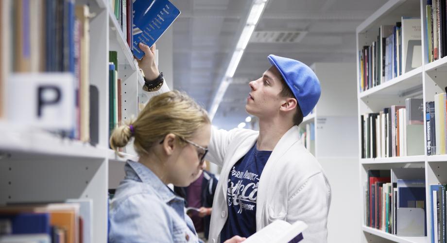Kuvituskuva, nuoret tutkimassa kirjoja kirjastossa