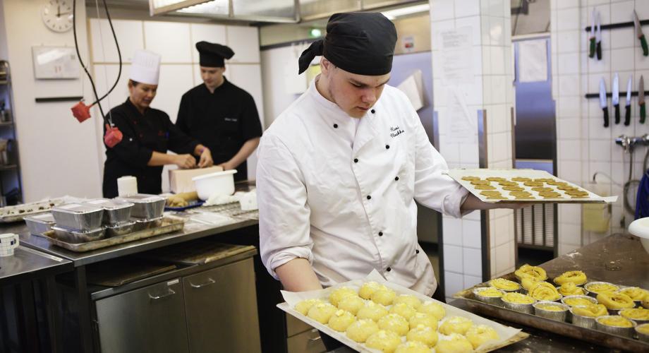 Kuvituskuva, kokki asettelee peltejä pöydälle