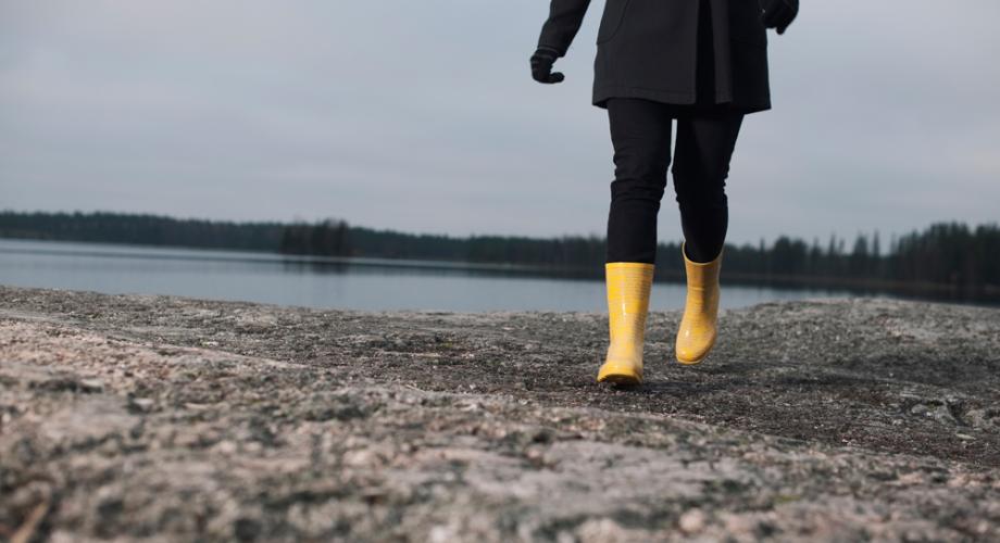 Henkilö kävelee kalliolla keltaisissa kumisaappaissa