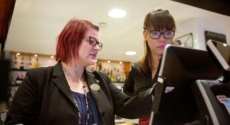 Opettaja ja opiskelija opetusravintolan kassakoneen ääressä