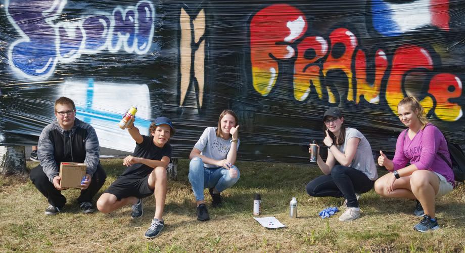 Kansainvälisen nuorisotapaamisen nuoria graffitia maalaamassa