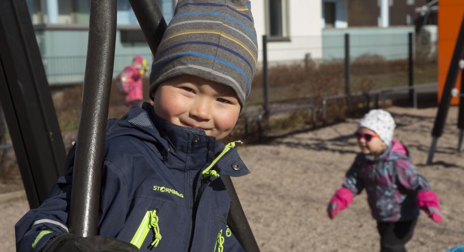 Poika keinuu päiväkodin pihalla