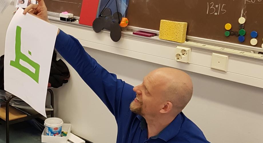 Professori Janne Saarikivi esittelee luokalle paperille piirrettyä arabialaista kirjainta
