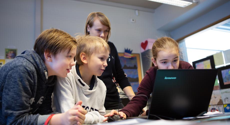 Oppilaat opettajan kanssa tietokoneen ääressä